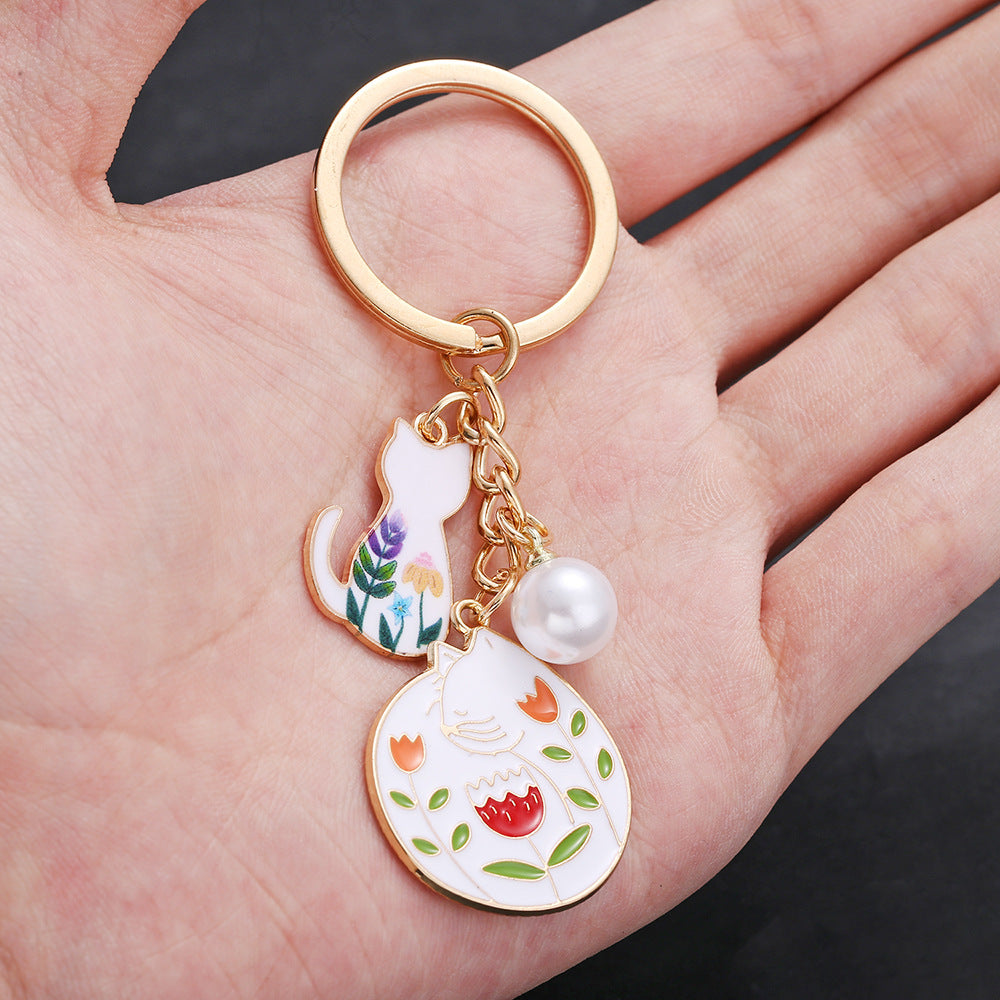 Wholesale oil drop cartoon cute flowers white cat pearl keychain metal jewelry pendant manufacturers