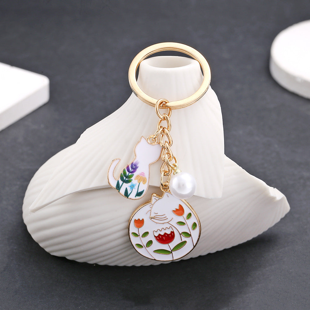 Wholesale oil drop cartoon cute flowers white cat pearl keychain metal jewelry pendant manufacturers