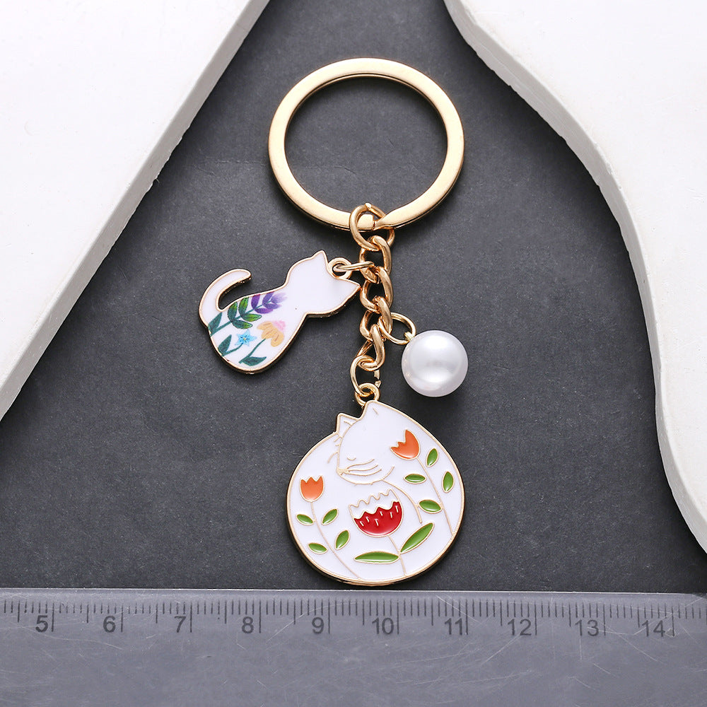 Wholesale oil drop cartoon cute flowers white cat pearl keychain metal jewelry pendant manufacturers